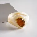 Detalle de brazalete de acrílico con piedra ámbar y acabado en marfil veteado - Blanco Roto-Café