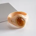 Primer plano de un brazalete de acrílico jaspeado con una piedra central ovalada ámbar. - Beige-Café