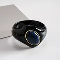Primo piano di un bracciale rigido in acrilico nero con una pietra in resina marmorizzata blu - Nero-Blu
