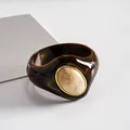 Dettaglio macro di bracciale in acrilico marmorizzato marrone scuro con inserto panna. - Marrone-Beige