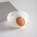 Detalle de un brazalete de acrílico blanco jaspeado con piedra ovalada color melocotón. - Blanco-Rosa