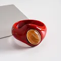 Dettaglio ravvicinato di un bracciale rigido rosso in acrilico con pietra ambra. - Arancione-Beige
