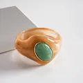 Dettaglio macro di bracciale in acrilico marmorizzato con pietra ovale in resina verde e oro. - Caffè Crema-Verde