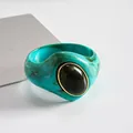Dettaglio macro del bracciale in acrilico turchese marmorizzato con pietra nera ovale - Blu-Verde