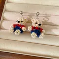 Detailed view of handcrafted beaded bear earrings in white, blue, and red colors. - Bear Stud Earrings / Silver Post-Multicolor