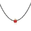 Detail view of a gold-plated necklace with a red apple pendant and black cube beads. - Apple Style