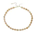 Vue détaillée d'un collier en acrylique avec perles marbrées beiges et séparateurs dorés. - Beige