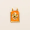 Close-up detail of a vintage style orange enamel Tarot heart pendant with golden evil eye motif - Yellow Sacred Heart