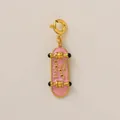 Gros plan d'un pendentif skateboard en émail rose avec placage à l'or 18 carats et texte. - Pendentif Skateboard