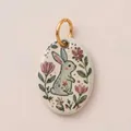 Detailopname van een ovale keramische hanger met handgeschilderd konijn en bloemen - Pioenrooskonijn Hanger