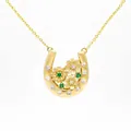 Close-up detail of luxury gold horseshoe necklace pendant with green floral gemstones - October Marigold Horseshoe Necklace