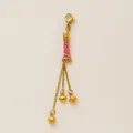 Macro view of a gold-tone pink enamel charm with dangling heart and star pendants - Lipstick Tassel Style / Lipstick Pendant
