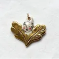 Detailed close-up of a unique golden winged pendant with a hand-painted ceramic face - Leaf Portrait Pendant