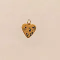 Primo piano di un ciondolo a cuore giallo con motivo a bacche e anello d'oro. - Ciondolo del cuore