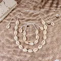 Dettaglio macro di set collana e bracciale fatti a mano con conchiglie su sfondo sabbioso - Set Collana e Bracciale Cordino Bianco / Bianco