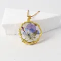 Elegant resin pendant necklace featuring real pressed flowers in blue and purple - July