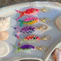 Vibrant handmade beaded fish pendants with gold-tone clasps in ocean summer style. - Small Fish Pendant / Purple Green