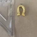 Close-up of a golden horseshoe charm pendant next to a ruler showing accurate size details - Horseshoe Pendant Only (Without Chain)