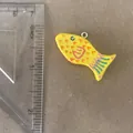 Detail view of a hand-painted yellow fish pendant with colorful patterns next to a ruler. - Little Fish Pendant Only (Without Chain)