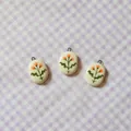Detail view of three oval white pendants with hand-painted orange flowers on gingham - 10 Oval Orange Blossom Pendant
