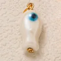 Primer plano de un colgante de pez blanco crema con ojo turco azul y enganche dorado. - Colgante Ojo Turco de Esmalte