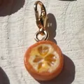 Gedetailleerd zicht op miniatuur sinaasappelschijfje bedel met gouden karabijnsluiting. - Sinaasappel Hanger Zonder Ketting