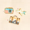 Detail of travel-themed enamel pins with a camera, airplane, and wave-print suitcase. - Suitcase Style(9)