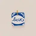 Nahaufnahme eines quadratischen blau-weißen Keramikanhängers mit Luck-Schriftzug - Nr. 5 Luck Anhänger