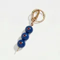 Detail van deze luxe blauwe kralen sleutelhanger met rode stenen en gouden haak - Donkerblauwe Olijf met Rode Steen