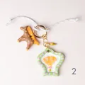 Detail showing hand-painted ceramic-style charms with a seashell and star motif. - Hot Air Balloon Shell Charm