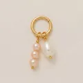 Gros plan d'un pendentif anneau doré avec perles roses et blanches sur fond beige - Pendentif Perle Ronde Rose / Rose et Blanc