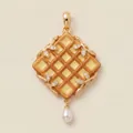 Detail of a creative waffle-shaped pendant with golden leaves and a white pearl drop. - Waffle Pendant