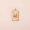 Détail d'un pendentif fer à cheval doré avec zircon bleu et lettres gravées style chic. - Style Fer à Cheval de Poker / Or