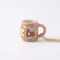 Detailed view of the miniature girl scene inside a pink ceramic mug pendant necklace. - Pink Green Flower Little Chef Mug Style