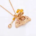 Nahaufnahme einer aufklappbaren goldenen Croissant-Halskette mit einem kleinen Corgi im Inneren - Mango Corgi Öffnende Croissant-Halskette