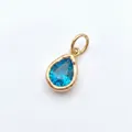 Gedetailleerd beeld van een vergulde druppelhanger met een facetgeslepen blauwe steen. - Alleen Hanger / December Turkoois Ovaal Charm