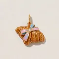 Close-up of a golden enamel croissant pendant with a charming pink and blue bow detail - Croissant Pendant