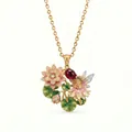 Detail of an intricate enamel fairy and lotus pendant with a red gemstone. - July Pink Lotus Necklace