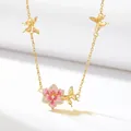 Detailed macro view of golden chain necklace with pink enamel flower and gold butterflies. - August