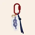 Detailed view of nautical bag charm featuring a blue rope knot on a white acrylic tag. - Burgundy Figure Eight Knot Style
