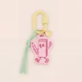 Detail shot of a pink acrylic keychain with a cute cartoon pencil character charm. - Cartoon Book Figure