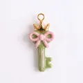 Détail en gros plan d'une clé en émail vert macaron avec couronne et un nœud rose - Style Clé Couronne / Vert menthe