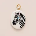 Detail view of hand-painted enamel zebra pendant with gold ring in a white oval ceramic style - Zebra Head Oval Pendant