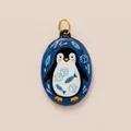 Close-up of hand-painted enamel penguin pendant with fish and ice cube motifs - Ice Cube Penguin Oval Pendant