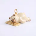 Detailansicht eines niedlichen Emaille-Bären, der auf einem goldenen Tastatur-Anhänger schläft - Bär auf Tastatur Anhänger