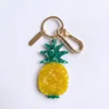 Primer plano detallado de un llavero de piña de acrílico amarillo con herrajes dorados - Colgante de Piña
