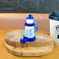 Blue and white lighthouse keychain with LED glowing feature placed on a wooden base - Blue