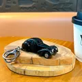 Glossy black vintage alloy car keychain toy pendant displayed on a wooden slice base - Beetle Car Charm / Black