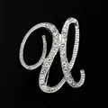 Primer plano de un broche de letra plateado con brillantes strass sobre fondo negro - Estilo Letra U (2255) / Plata U