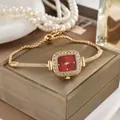 Close-up detail of an elegant gold square watch with a red dial and rhinestone drawstring band. - Gold Red